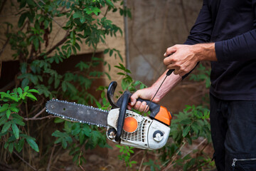 Close-up of woodcutter sawing chainsaw in motion, sawdust fly to sides. Man with the chainsaw. Dangerous job. Powerful chainsaw. Lumberjack hold chainsaw. Gardener lumberjack equipment.
