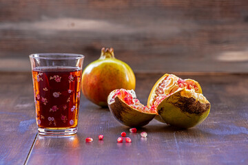 Pomegranate juice and pomegranates in glass on wooden background