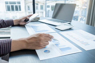 The hands of a male businessman are analyzing and calculating the annual income and expenses in a financial graph that shows results To summarize balances overall in office