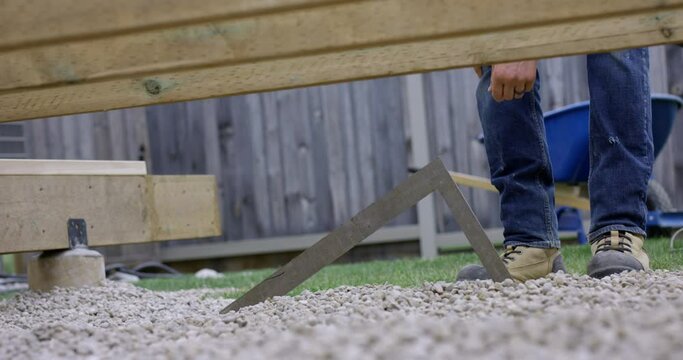 Man building deck levelling rock aggregate - wide shot