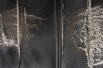 Torn black fabric on a leather office armchair background texture. worn upholstery chair
