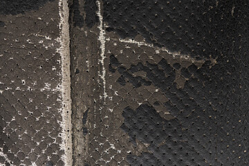 Torn black fabric on a leather office armchair background texture. worn upholstery chair