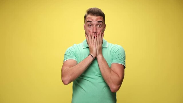 handsome shocked casual guy slapping his face, puffing his cheeks and can not believe the situation on yellow background