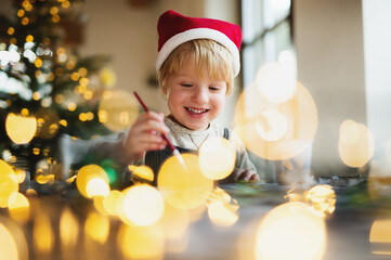 Portrait of small boy indoors at home at Christmas, painting pictures.