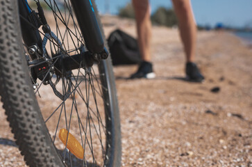 Bicycle wheel on a beach and male legs on background