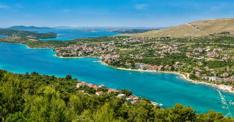 Naklejka na ściany i meble Panoramic view of the beautiful coastline of the Adriatic Sea and coastal resort town of Grebastica, Croatia, situated on a long bay between Split and Sibenik, viewed from the D8 highway.