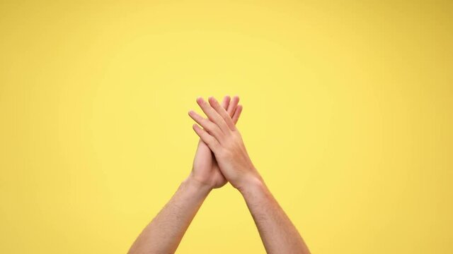 two arms are clapping, pointing at the camera and clapping again on yellow background