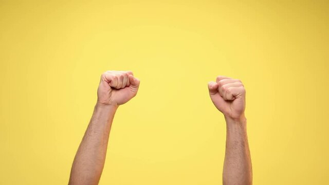two arms with closed fists are celebrating succes on yellow background