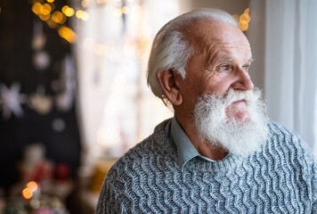 Front view of sad and lonely senior man indoors at home at Christmas.