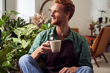 Florist in mask holding plants in pots