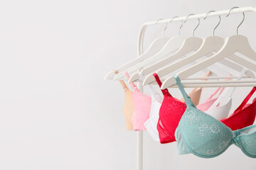 Clothes rack with stylish bras on light background - obrazy, fototapety, plakaty