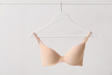Hanger with stylish bra on light background - obrazy, fototapety, plakaty
