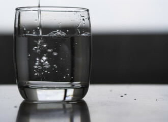 Drinking water in a clear glass On a gray background