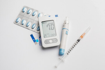 Glucometer, lancet pen, pills and syringe on white background. Diabetes concept