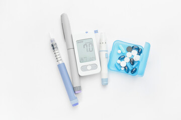 Glucometer, lancet pens, pills and syringe on white background. Diabetes concept