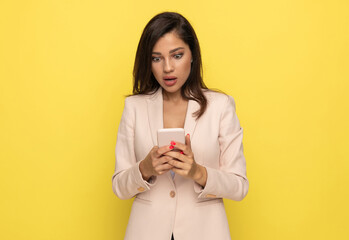 shocked young businesswoman in pink suit reading messages