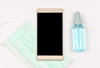  blank screen of mobile phone on white background with medical face mask and alcohol sprey. Covid19 prevention , new normal and communication.