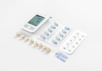 Glucometer with pills, strips and word DIABETES on white background