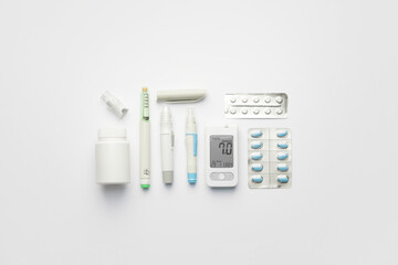 Glucometer, pills, lancet pens and syringe on white background. Diabetes concept