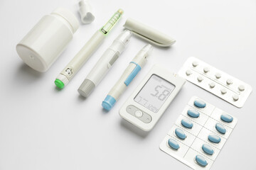 Glucometer, pills, lancet pens and syringe on white background. Diabetes concept