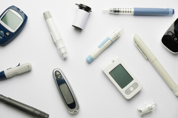 Glucometers with lancet pens and syringe on white background