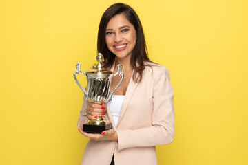 proud businesswoman in pink suit holding trophy