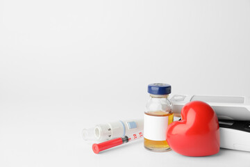 Glucometers with heart, bottle of insulin, lancet pen and syringe on white background. Diabetes concept