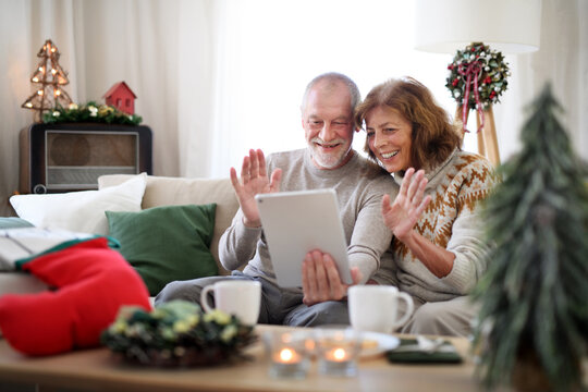 Front View Of Senior Couple Indoors At Home At Christmas, Having Video Call With Family.