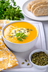 Pumpkin cream soup on white wooden cutting board and a little pumpkin. Autumn still life.