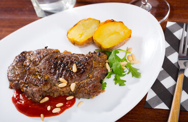 Beef steak with ketchup and pine nuts, served with baked potatoe