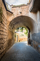Fototapeta na wymiar Narrow old street under the arch of the bridge in Orvieto, Umbria, Italy