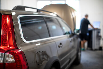 Car mechanic running a diagnostic on a car in a repair shop/car garage (shallow DOF/color toned image)