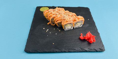 Sushi set California or Philadelphia served on a black board over pastel blue background.