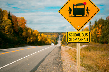 School bus stop ahead road sign. Yellow warning sign on the roadside. Highway in Ontario, Canada