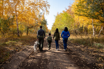 Family walk in the yellow woods with a dog.