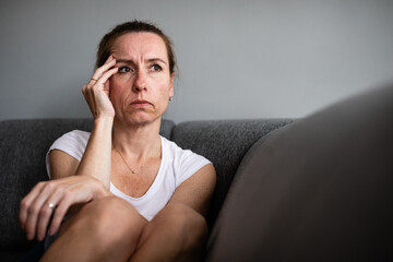 Obraz premium Depressed mid-aged woman at home feeling sad, lonely, anxious (color toned image)