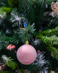 Pink ball with snowflakes and frost on a Christmas tree, vertical photo postcard. Winter seasonal holiday, christmas decoration, background design