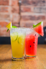 Watermelon and melon smoothies garnished with watermelon slices and mint leaves served in a glass on rustic wooden table
