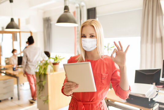 business, pandemic and health concept - businesswoman or creative female office worker in face protective medical mask for protection from virus disease with tablet pc computer showing ok hand sign