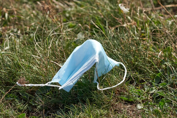 Used Medical face mask on the ground in the grass. Improperly dispose of used face mask. Nature...