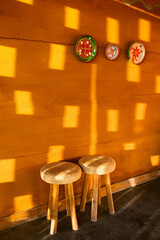 Red terracotta color clay wall with handmade souvenir plates as decoration and two wooden chair....