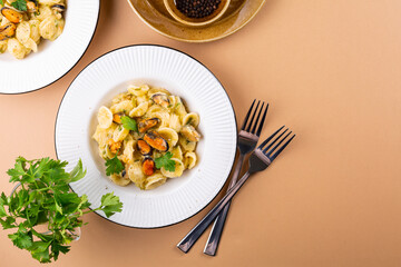Italian pasta orecchiette with mussels and potato and garlic sauce. Light terracotta background.