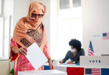 Islamic woman voter putting her vote in the ballot box, usa elections and coronavirus.