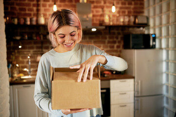 Online shopping, shipping and home delivery concept. Happy joyful young woman standing against cozy...