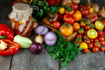 Tomatoes, peppers, onions on the table. Preservation of the autumn harvest of vegetables. Glass jar with pickled tomatoes. Wooden background. Vegetable food. Still life. Tomato of different varieties.