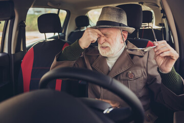 Portrait of his he nice exhausted tired sad depressed grey-haired man driving car in traffic jam...