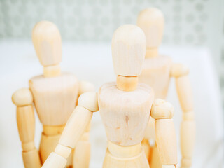 A figurine of a wooden man on hinges against the background of two other figures. Photo with focus...