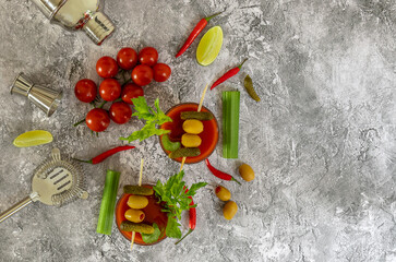 Top view of tomato Bloody Mary cocktail drink with fresh celery, pickles, olives, and lime.