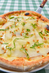 Pear and cheese pizza over green plaid table cloth. Delicious unique recipe. Traditional Italian cuisine Italian concept