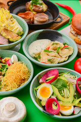 Variety of food dishes on bright green background. Table covere with food flat lay, top view, frame.